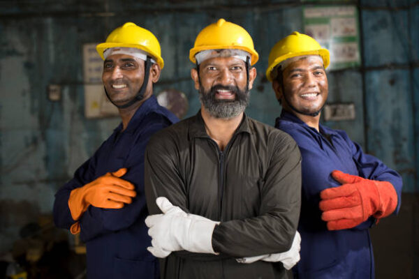 Three confident male engineers standing together in solidarity at factory Three confident male engineers standing together in solidarity at factory